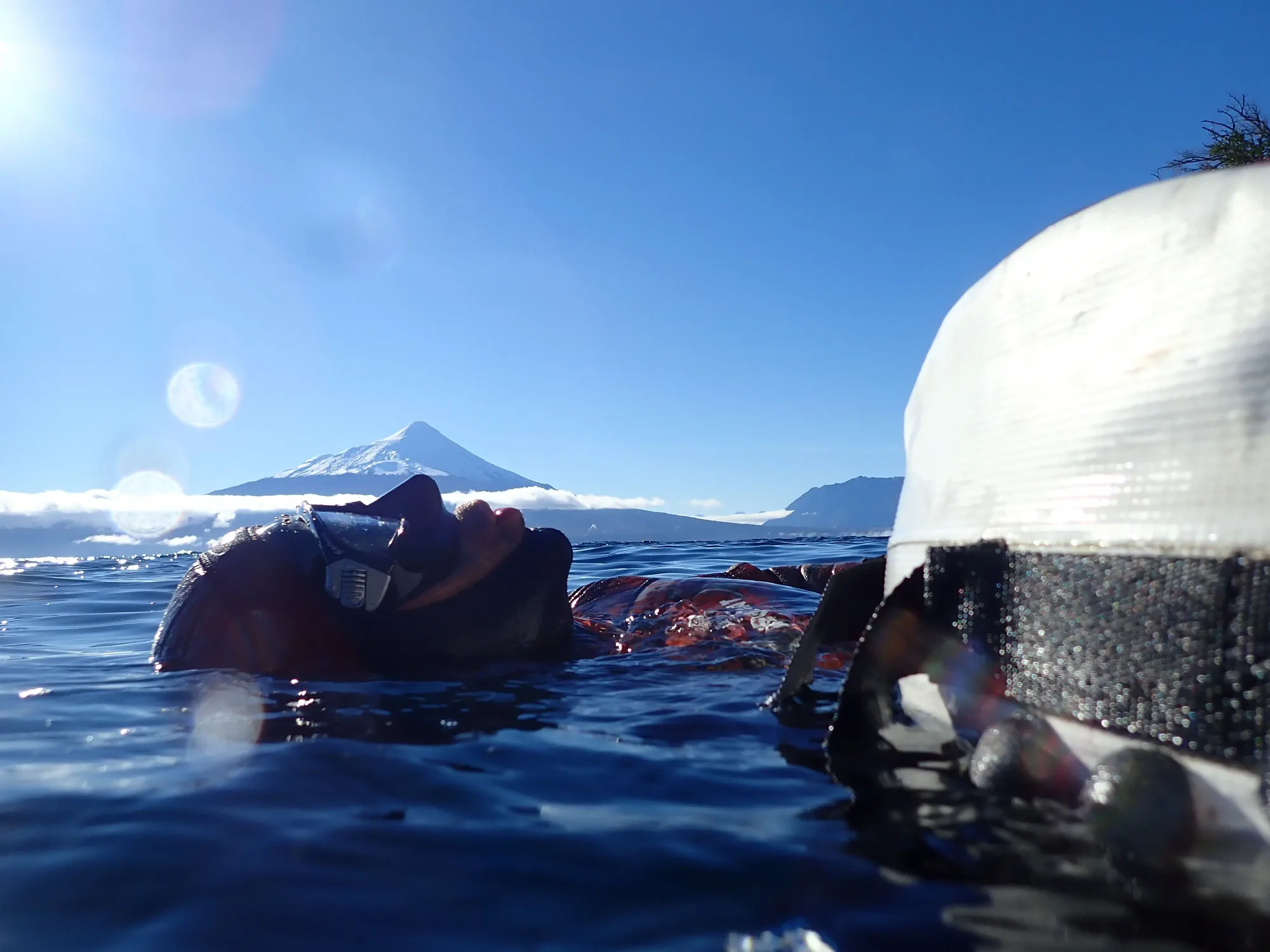 Sebastián Álamos flotando en la superficie del lago antes de una inmersión, con el volcán Osorno al fondo