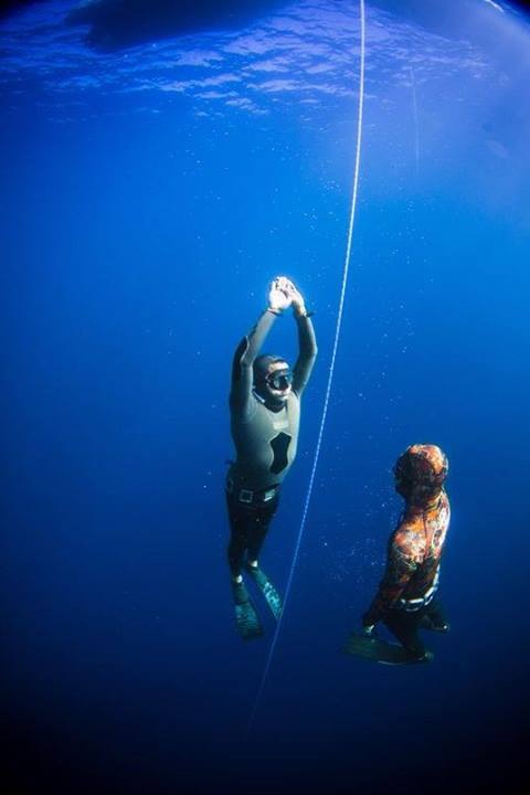 Dos apneístas descendiendo juntos por la línea en agua azul profunda