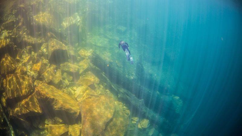 Luz del sol atravesando el agua sobre un fondo de rocas